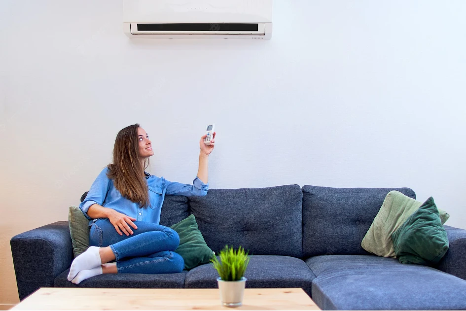 femme sur un canapé allumant sa climatisation réversible